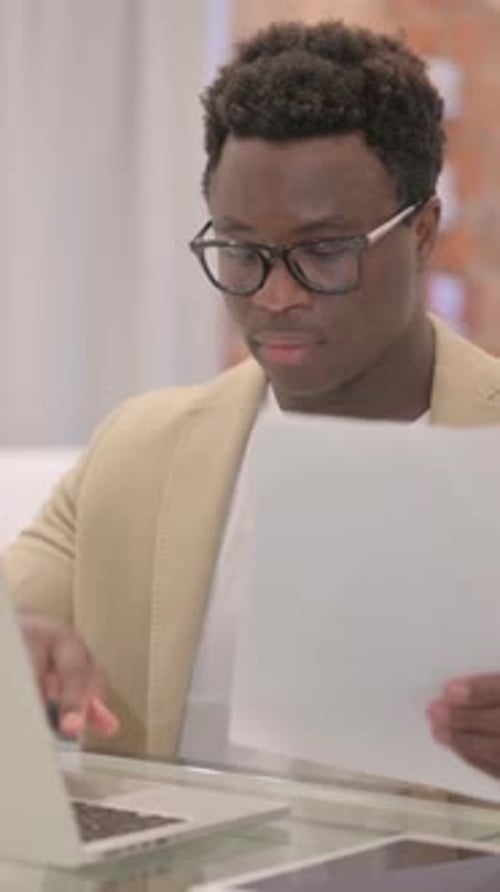 Young Adult Man Working with Laptop and Documents