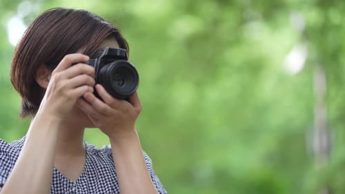 Smiling Woman Holding a Camera Outdoors