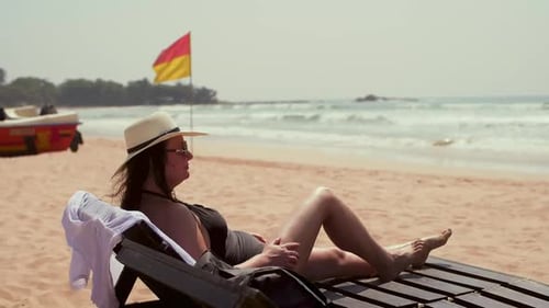 Relaxed Woman in Hat Glasses Enjoys Beach Ocean Vacation Lying in Deckchair