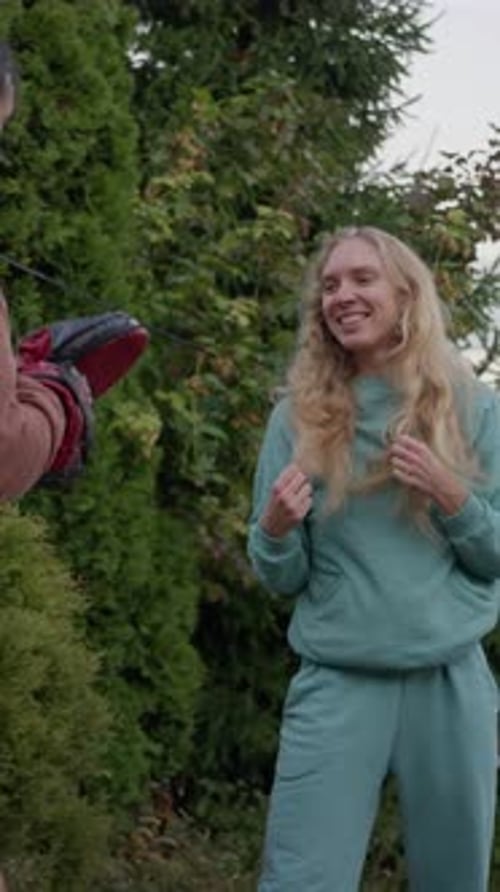 Woman practices kickboxing with trainer in backyard