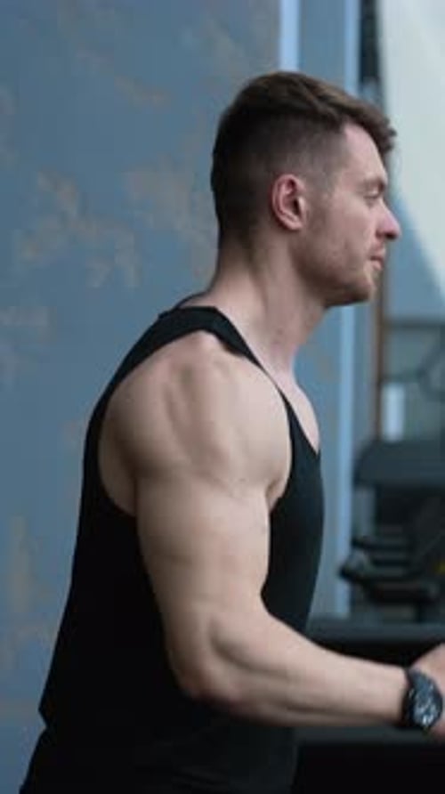 Man running on treadmill in gym. Young athletic man exercising and running on treadmill in sport gym