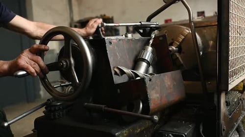 Close-up of worker's hands operating industrial machinery in workshop.