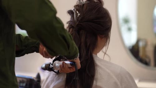 Woman Getting Hair Curled by Hairdresser at Salon