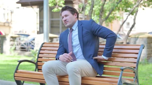 Man in Suit Experiencing Back Pain on Bench