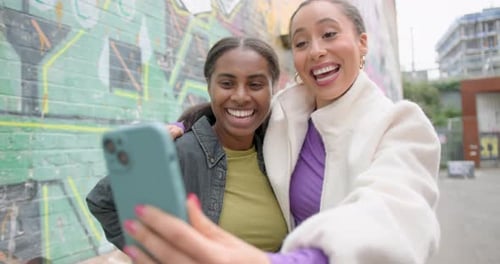Two Female Friends Joyful talking on video call on street