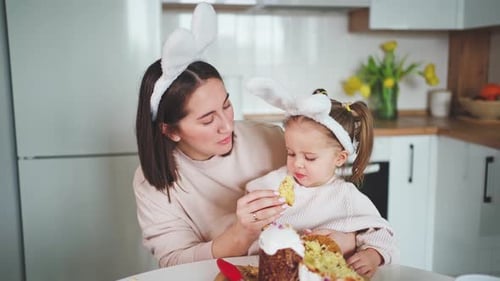 Beautiful daughter and mother are smiling and eating traditional easter cake. Happy Easter
