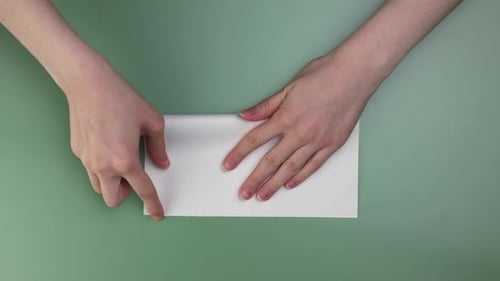 woman's hands folding origami on the green background speeded video
