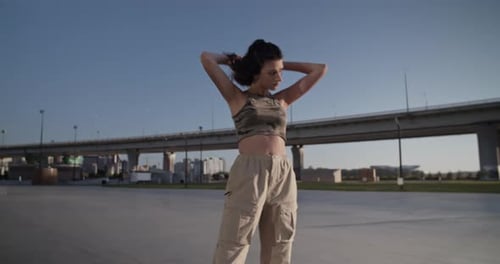 Young Woman Puts on Headphones in Urban Environment