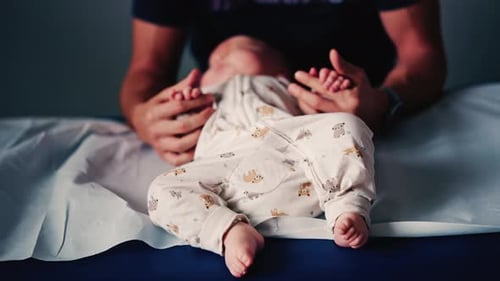 Man Holding Arms of Infant Lying on Table