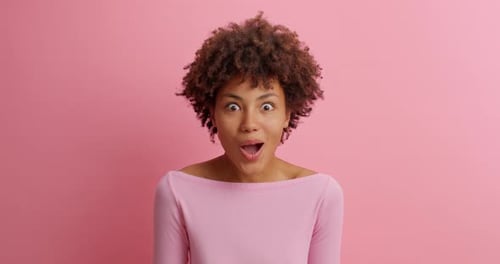 Surprised Woman with Curly Hair against Pink Background
