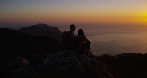 Couple, hiking and mountain top for adventure, night and sunset over ocean, climbers and silhouette