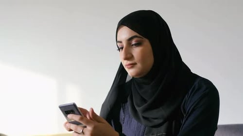Femme arabe utilisant une application mobile sur son téléphone portable intelligent. Fille du Moyen-Orient portant le hijab Abaya