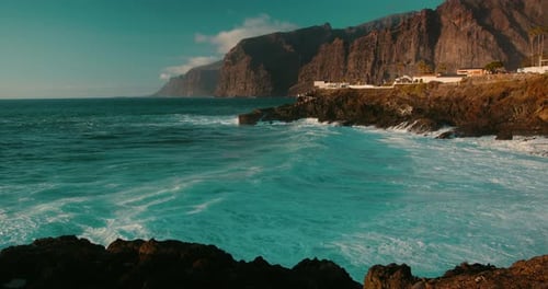 Ocean Waves Foam on Black Volcanic Rocks on Shore of Tenerife Island Closeup Blue Water Swell