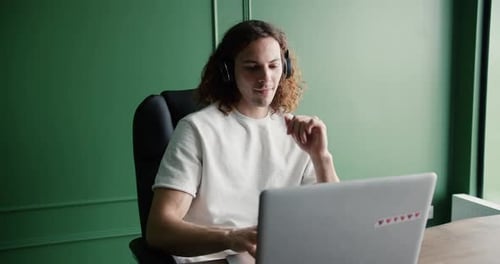 Young Adult Using Laptop with Headphones Indoors