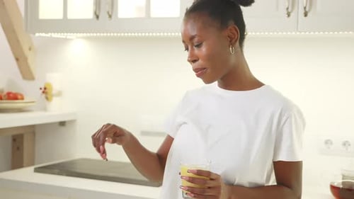 Woman Holding Juice Talking in Modern Kitchen