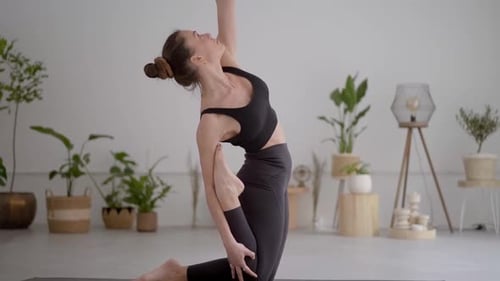 Side View of Young Caucasian Girl in Grey Sportswear Doing Yoga Onelegged Posture King Pigeon Pose
