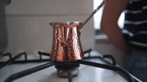 Traditional Turkish coffee in a copper pot, Young woman pouring coffee into a cup