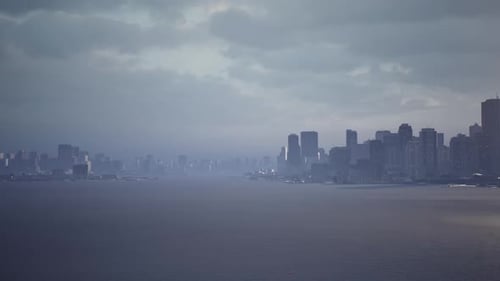 City Skyline View Under a Cloudy Sky Over Calm Waters at Dusk