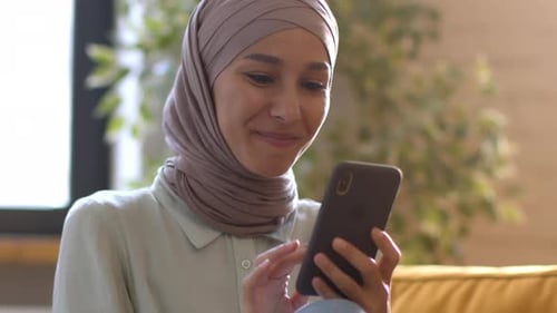 Woman in Headscarf Using Smartphone and Smiling