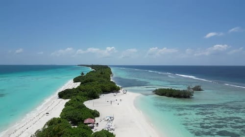 Mangrove vegetation and long white sand beach amid sky blue water of Dhigurah Island