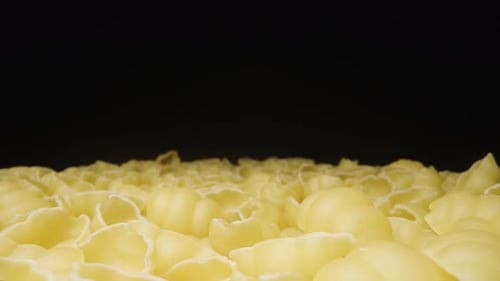 Dry gnocchetti pasta rotates, Scattered evenly on the Table, on a Black background, Close-up.