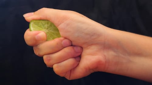 Hand Squeezing Lime on Black Background