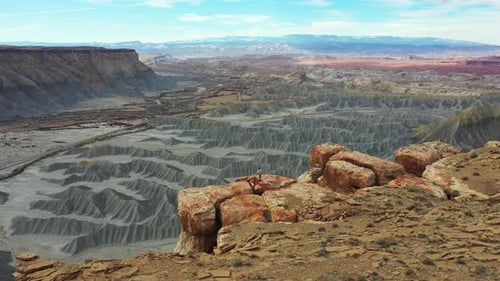 Aerial View of Man Standing on Top of The Cliff Above Abyss and Desert Landscape of Utah USA, Orbit