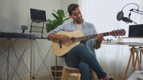 Man Playing Guitar and Singing in Home Studio