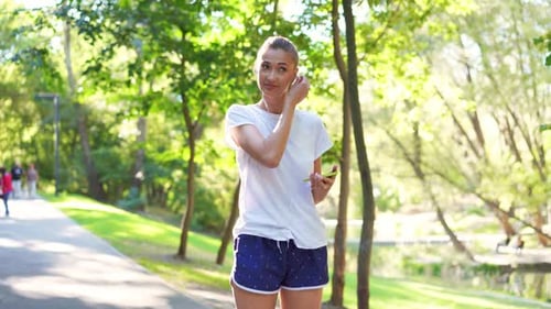 Happy Woman Athlete Put on Earphones and Jogging in Park