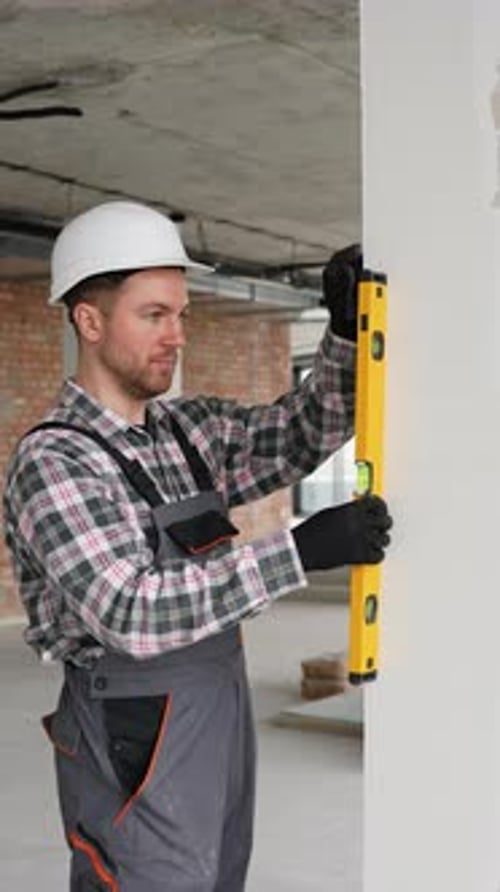 Construction Worker Checking Wall Straightness with Spirit Level