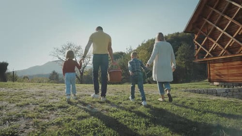 Family Stroll with Picnic Basket Towards Rural Cabin