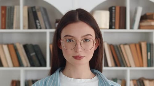 Smiling Woman with Eyeglasses in Front of Bookshelf