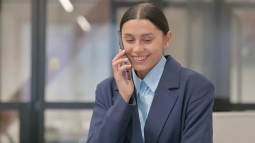 Woman in Blazer Talks on Smartphone at Workplace