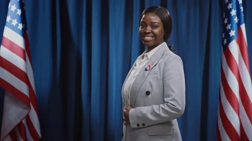 Smiling Woman Standing In Front of American Flags