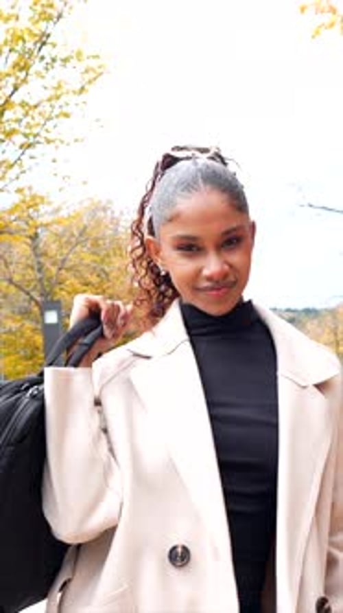 Young businesswoman carrying laptop bag walking along the city