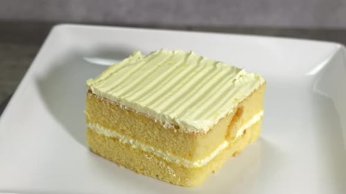 A Medium Top Down view of a slice of Yellow Cake Rotating on a Table.