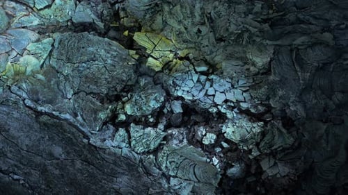 Cracked solid rock from solidified lava field, colored surface minerals