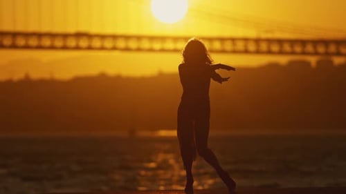 A Woman is Dancing on a Pier in the Evening