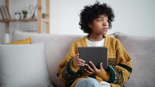 Woman with Tablet Sitting on Sofa Indoors