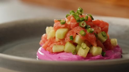 Chilean Salmon Tartar Seviche with Avocado and Cucumber on Purple Cream Cheese Adding Green Onion on