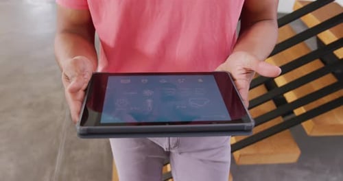 Video of biracial man checking weather on tablet and looking around at holiday home interior