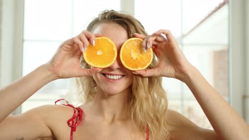 Playful Woman with Orange Halves Over Eyes