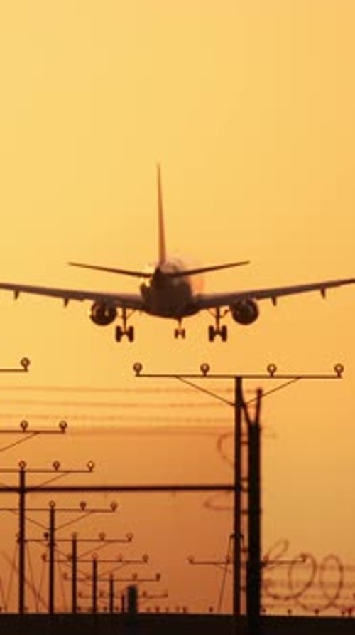 View a Vertical Video of an Airplane Landing at Sunset Showing Its Approach and Descent