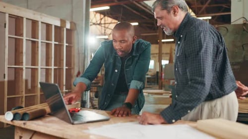 Men Collaborate Using Laptop in Workshop Setting