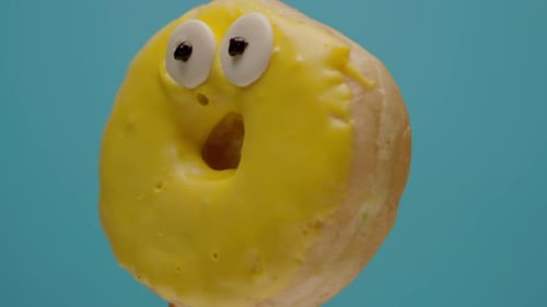 Funny Yellow Donut with Eyes Rotating on Blue Background in Slow Motion
