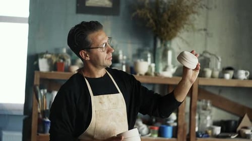 Ceramic Artist Inspecting Pottery in Studio