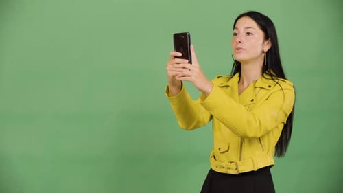 A Young Beautiful Caucasian Woman Takes Pictures with a Smartphone Green Screen Studio