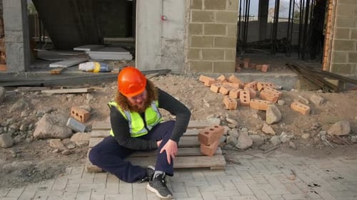 Injured Construction Worker Sits at Construction Site