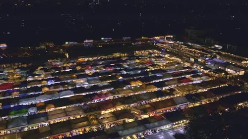 Panning Over Rows of Colorful Market Tents and Food Stalls at Night