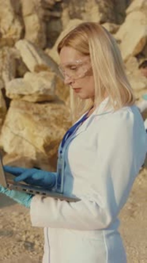 Female Scientist Works On Laptop in Rocky Desert